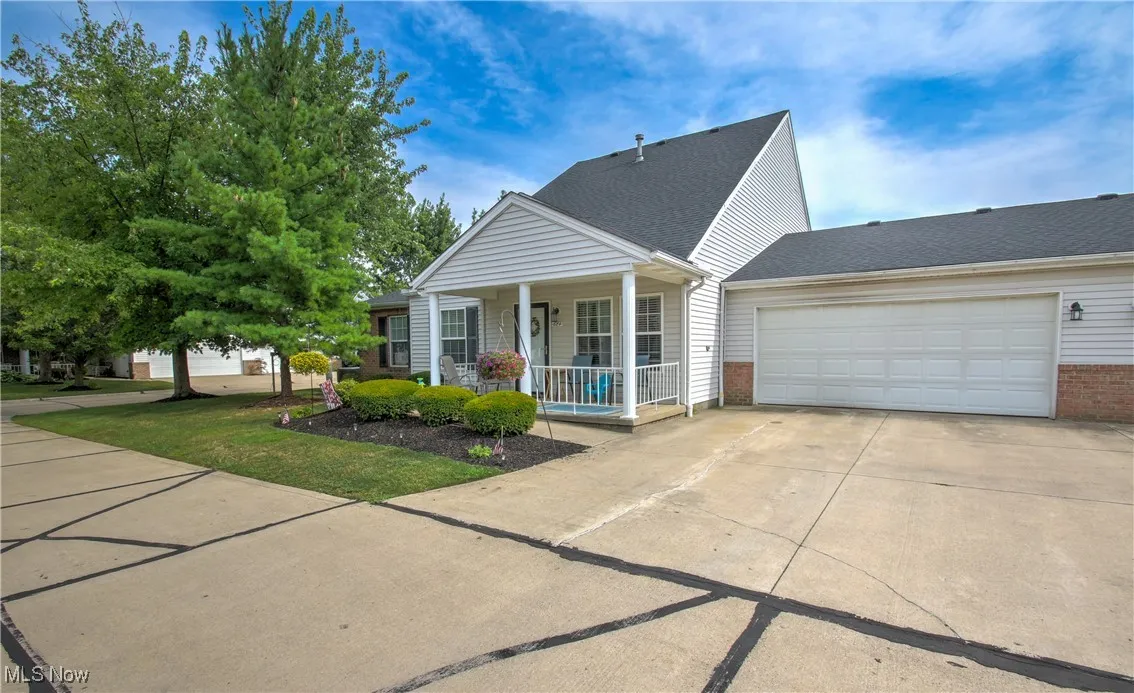 View of front of home featuring a porch, driveway, roof with shingles, brick siding, and an attached garage