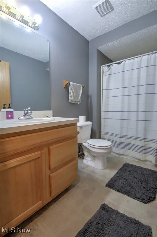 Bathroom featuring a textured ceiling, vanity, and a shower with shower curtain