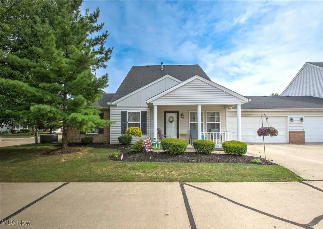 View of front of property featuring a porch, driveway, a front yard, and a shingled roof