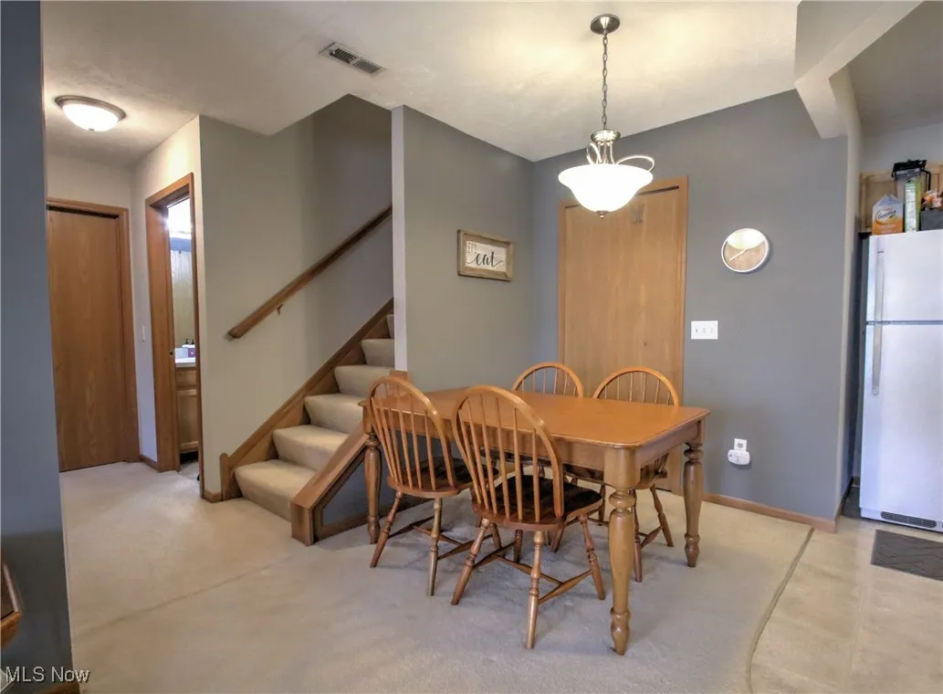Dining space featuring stairs and light colored carpet
