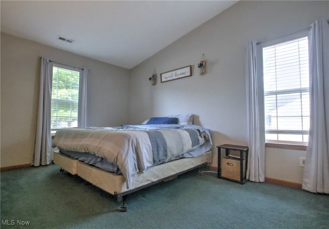 Carpeted bedroom featuring lofted ceiling and baseboards