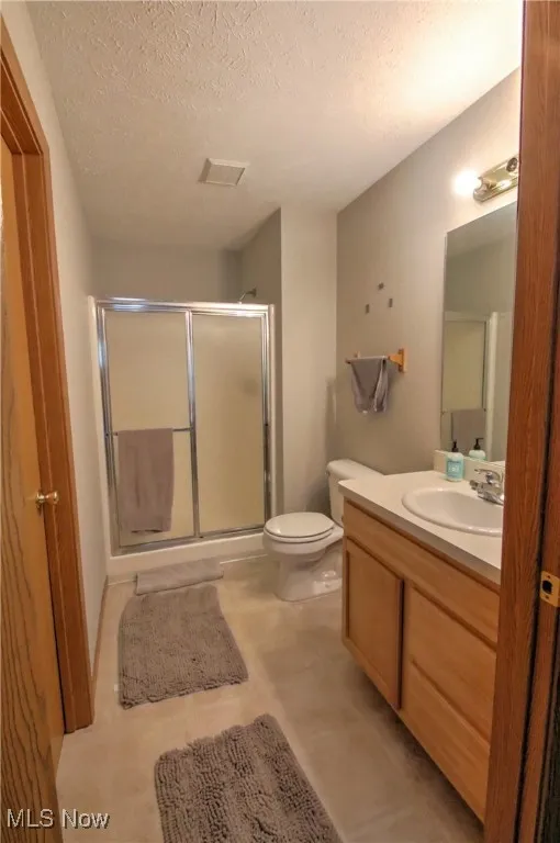 Bathroom with a textured ceiling, a shower stall, and vanity