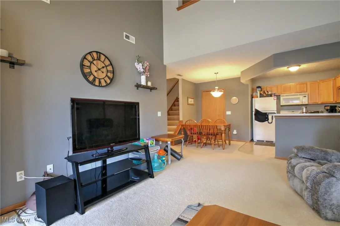 Living room featuring light carpet, stairs, and a towering ceiling