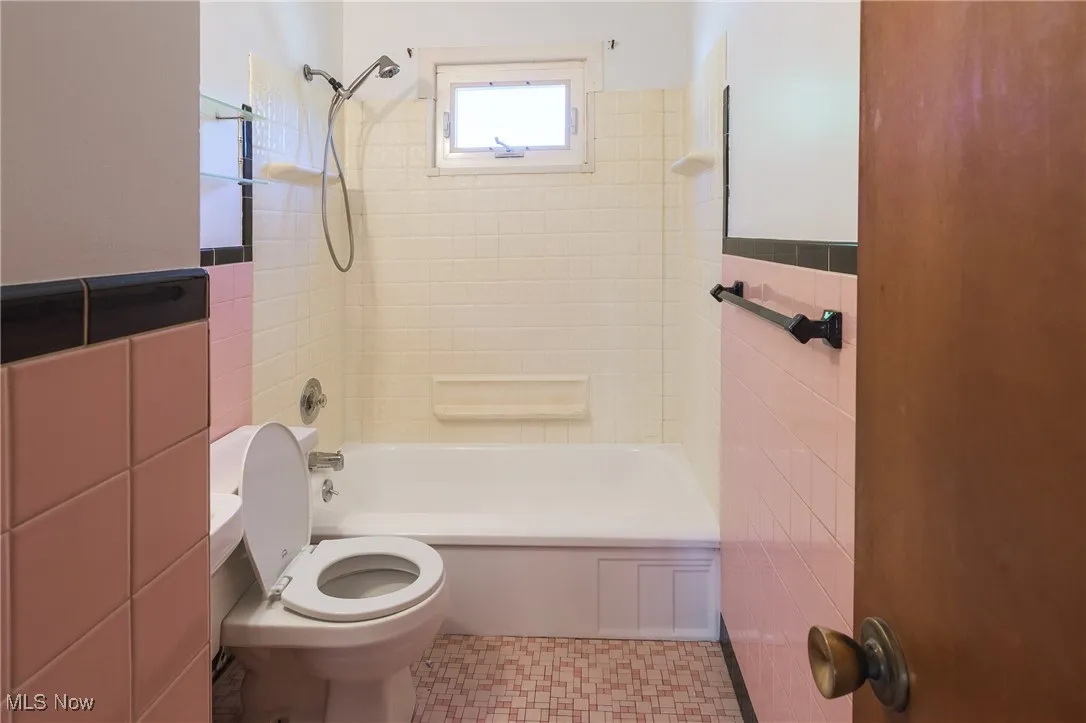 Full bath with tile walls,  shower combination, and wainscoting