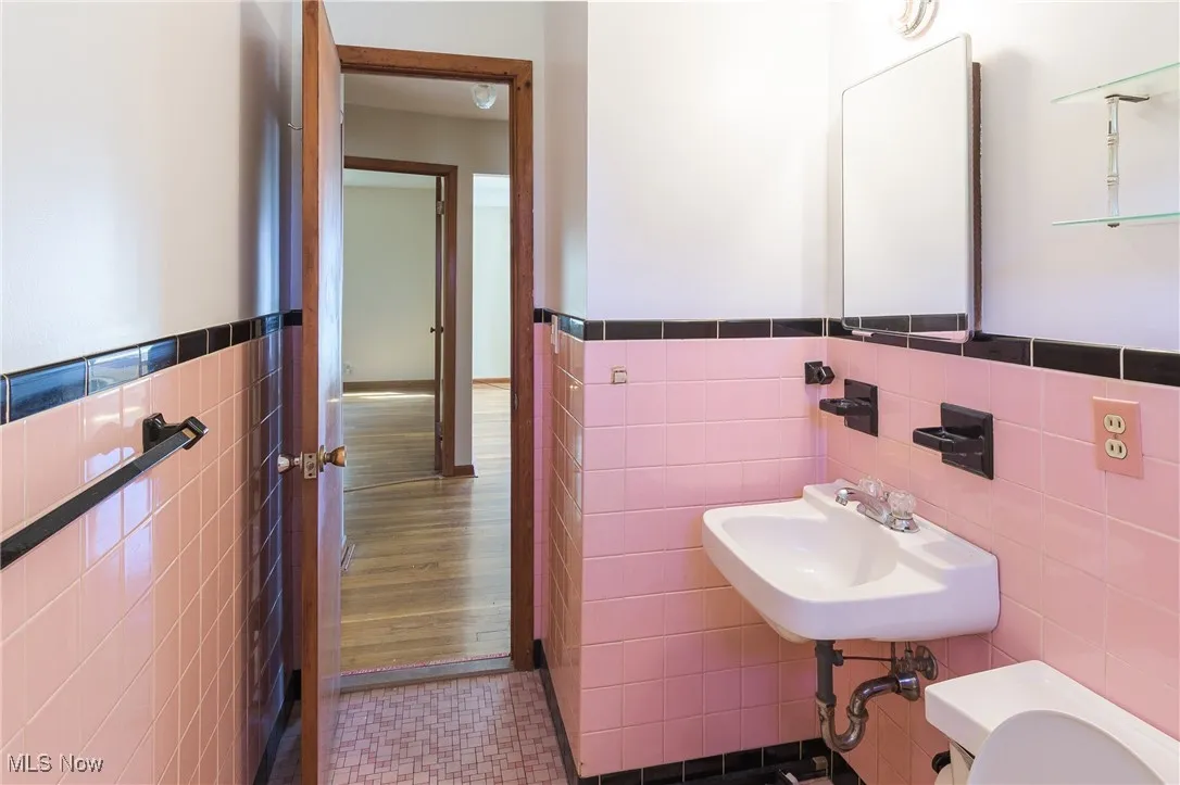 Half bathroom with tile walls, wainscoting, and tile patterned flooring