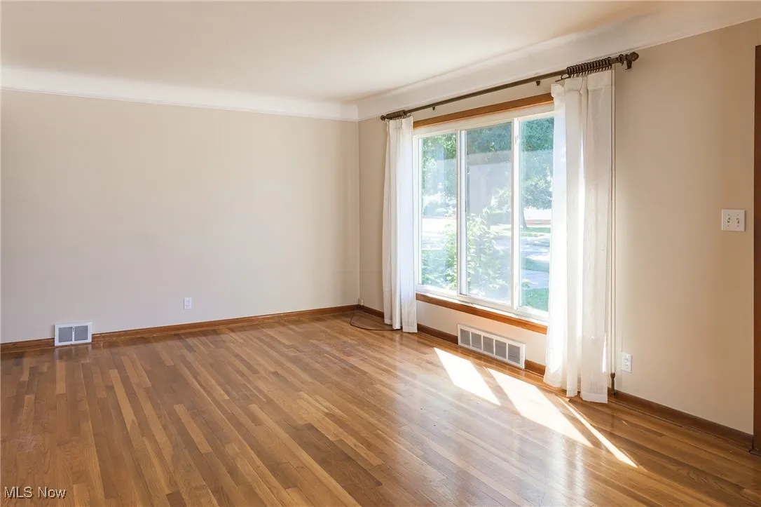 Spare room featuring wood finished floors and crown molding