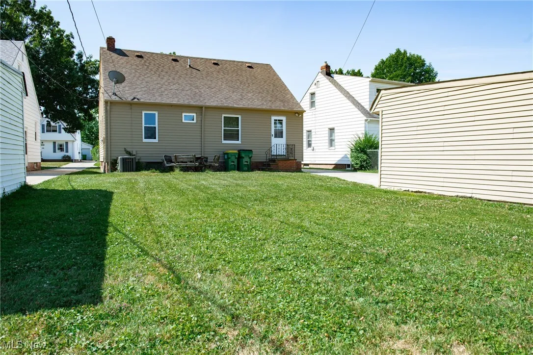 Rear view of property with a lawn, roof with shingles, and a chimney