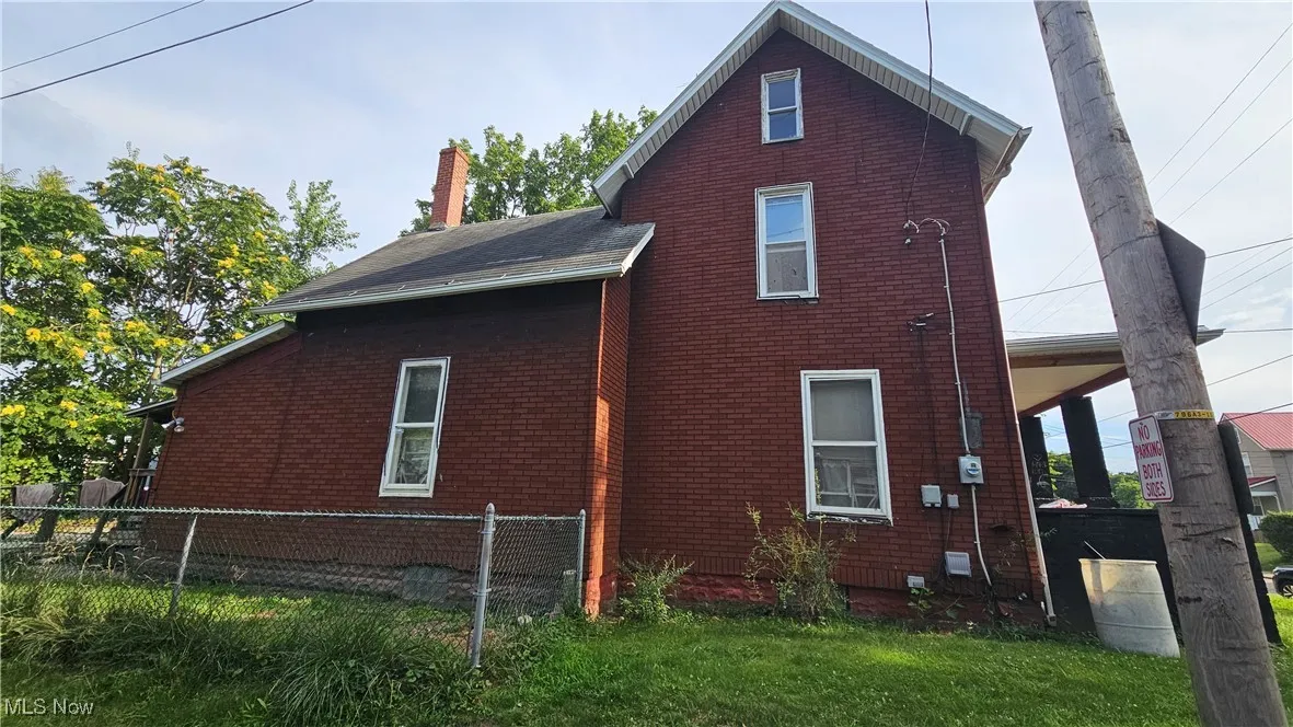 View of side of home featuring a chimney and brick siding