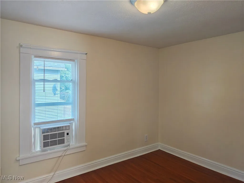Unfurnished room featuring dark wood-type flooring and cooling unit