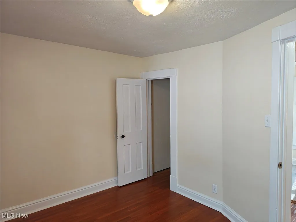 Empty room with a textured ceiling and dark wood-style flooring