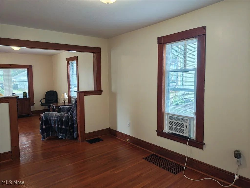 Unfurnished room featuring dark wood-style floors, healthy amount of natural light, and cooling unit