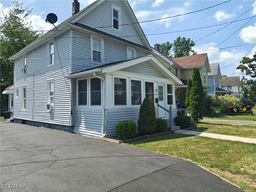 View of front of property featuring a chimney, a front yard, and a sunroom