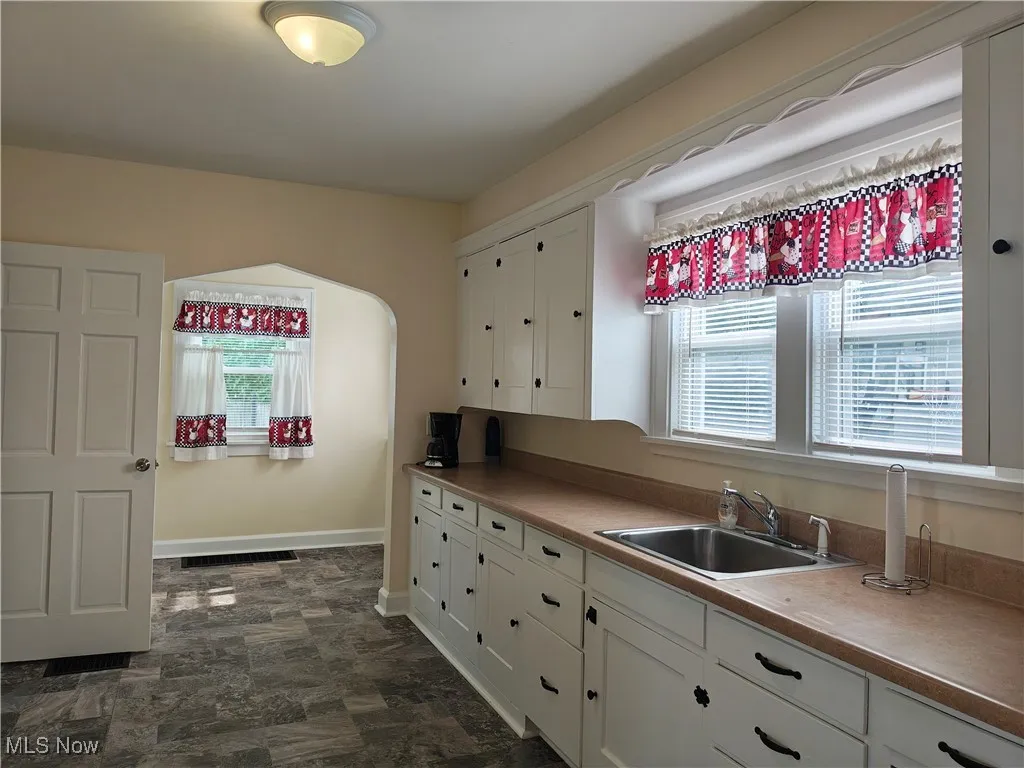 Kitchen with white cabinetry and stone finish floors