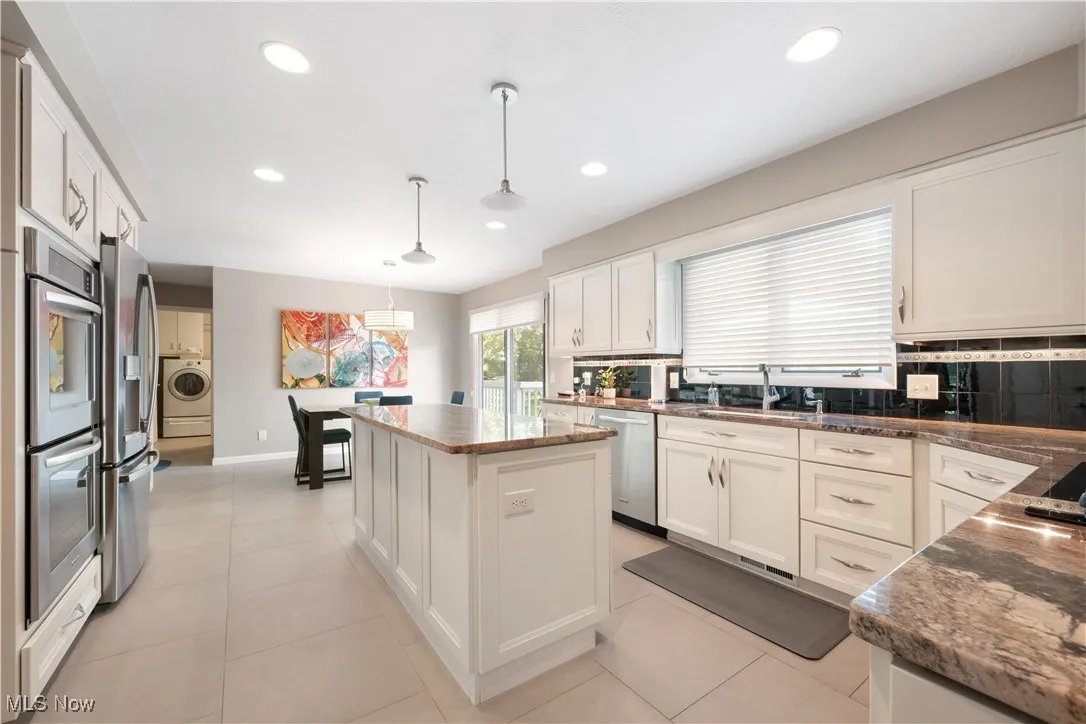 Kitchen with a center island, white cabinets, stainless steel appliances, recessed lighting, and washer / clothes dryer
