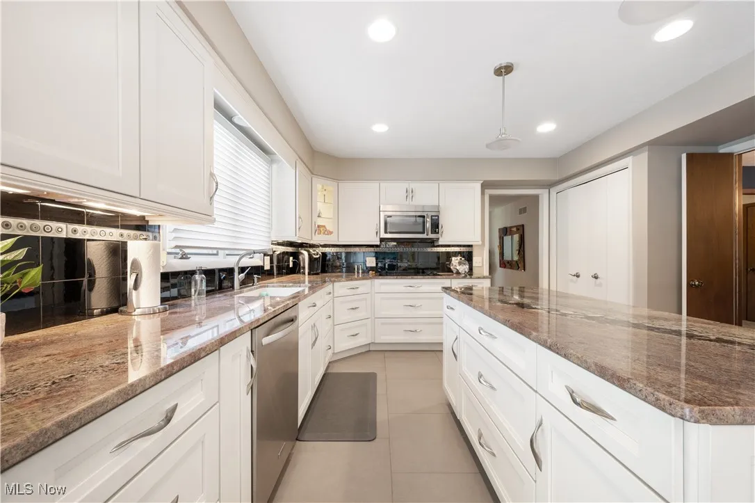 Kitchen featuring recessed lighting, stainless steel appliances, white cabinetry, tasteful backsplash, and stone countertops