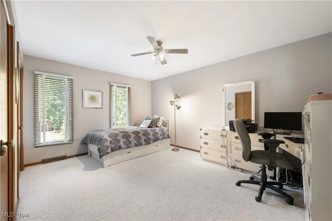 Carpeted bedroom featuring an office area and ceiling fan