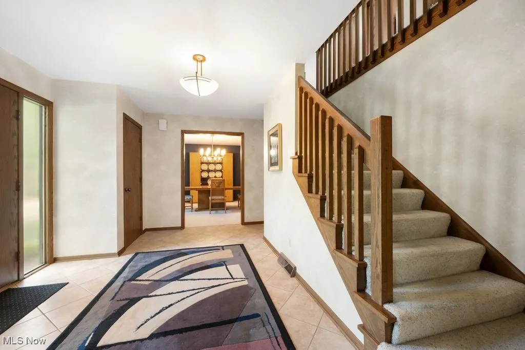 Staircase with a chandelier and tile patterned floors