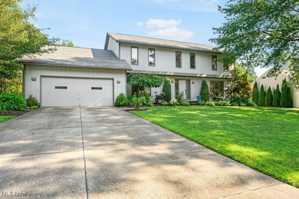 View of front of property with an attached garage, a front lawn, and driveway