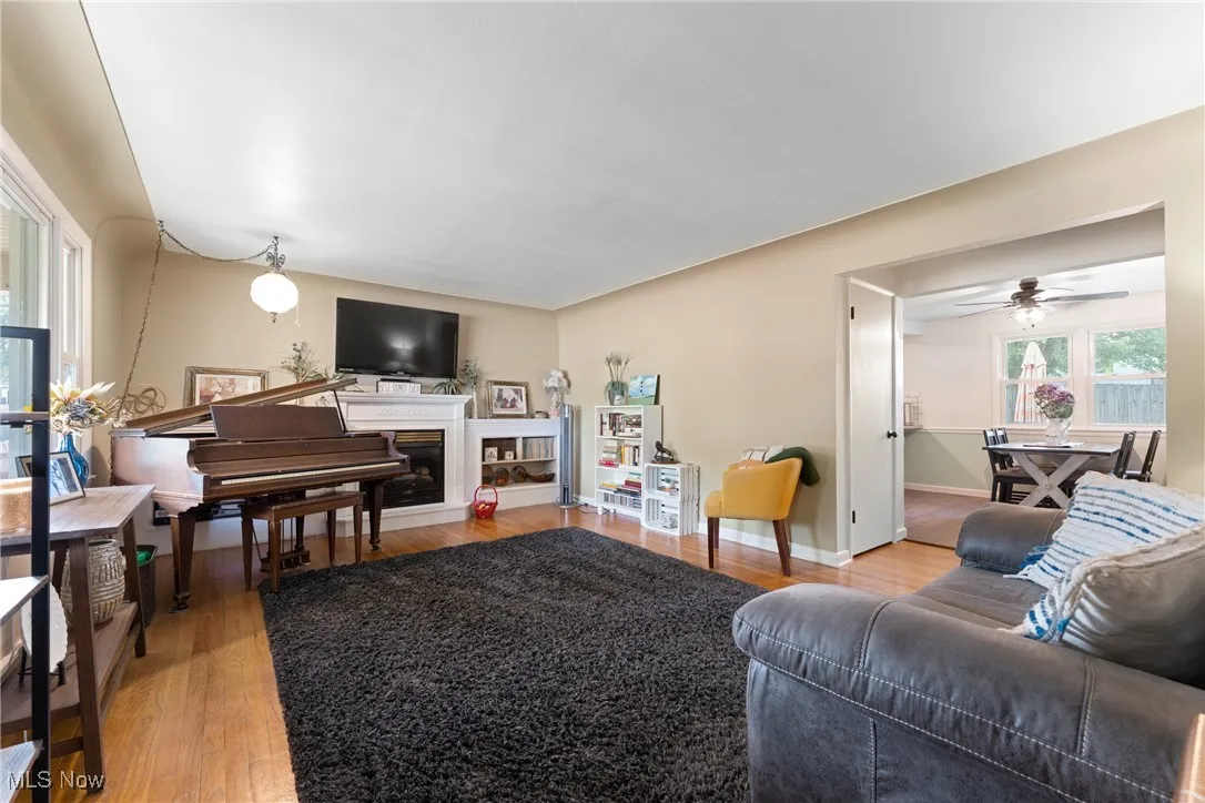 Living area with light wood-style floors, a fireplace, and ceiling fan