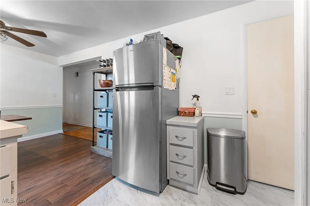 Kitchen with freestanding refrigerator, light countertops, ceiling fan, gray cabinets, and light wood-style flooring
