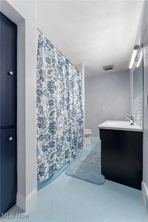 Full bath featuring vanity, tile patterned floors, a textured ceiling, and a shower with shower curtain
