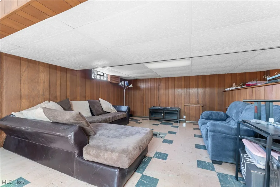Living room with a drop ceiling, tile patterned floors, and wooden walls