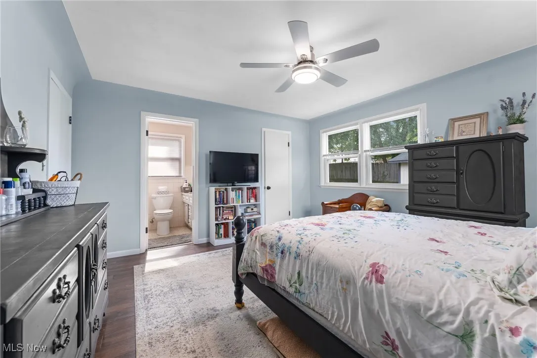 Bedroom featuring dark wood-type flooring, ensuite bath, and a ceiling fan