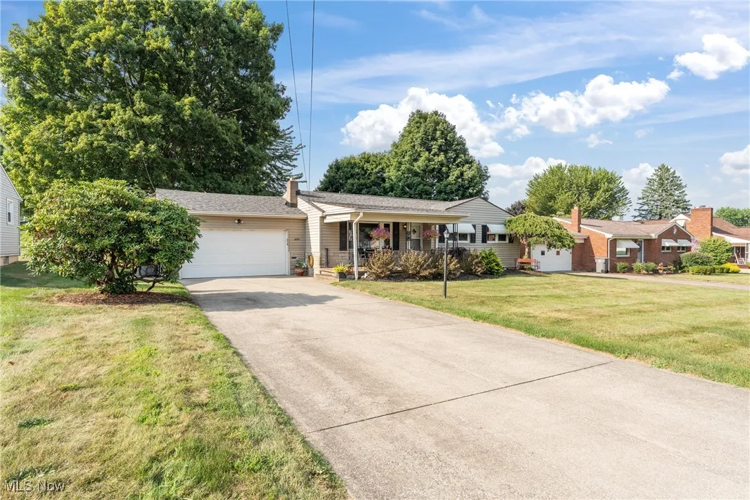 Ranch-style house with a garage, a porch, driveway, and a front yard