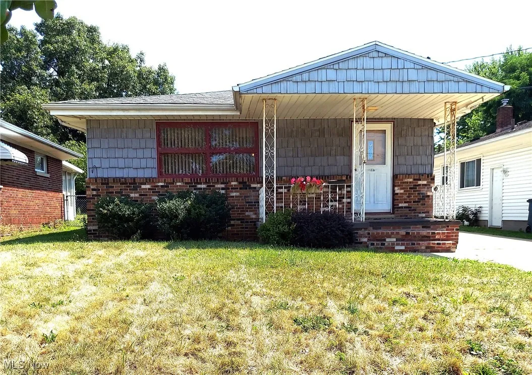 View of front of house with a front yard, brick siding, and covered porch