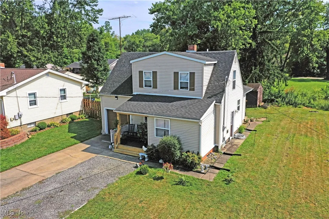 View of front of property featuring a shingled roof, a front lawn, driveway, and a chimney