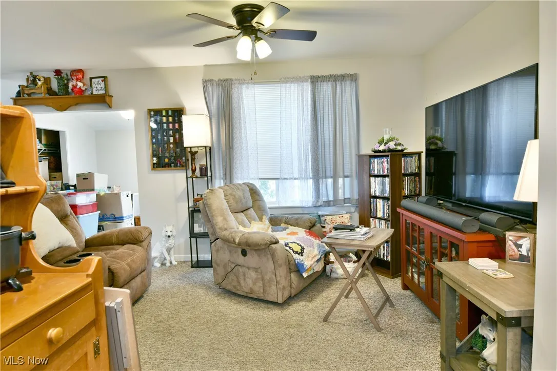 Living area with light colored carpet and a ceiling fan