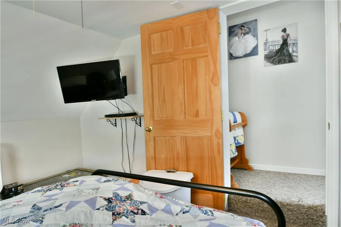 Carpeted bedroom with lofted ceiling and baseboards