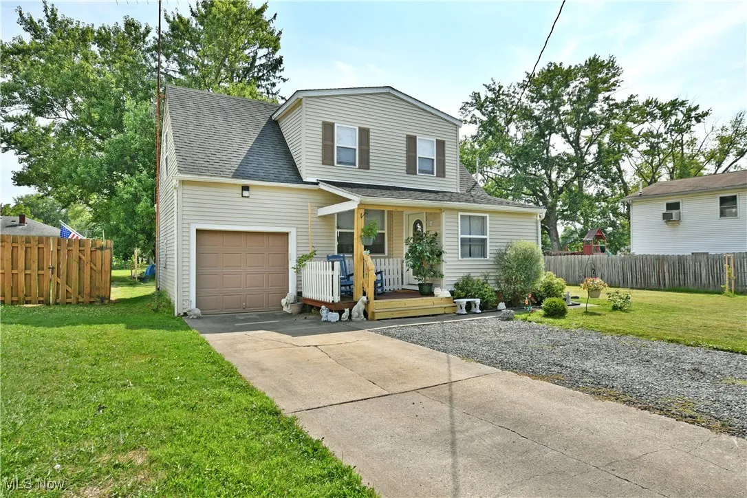 Traditional-style home with covered porch, driveway, roof with shingles, and an attached garage