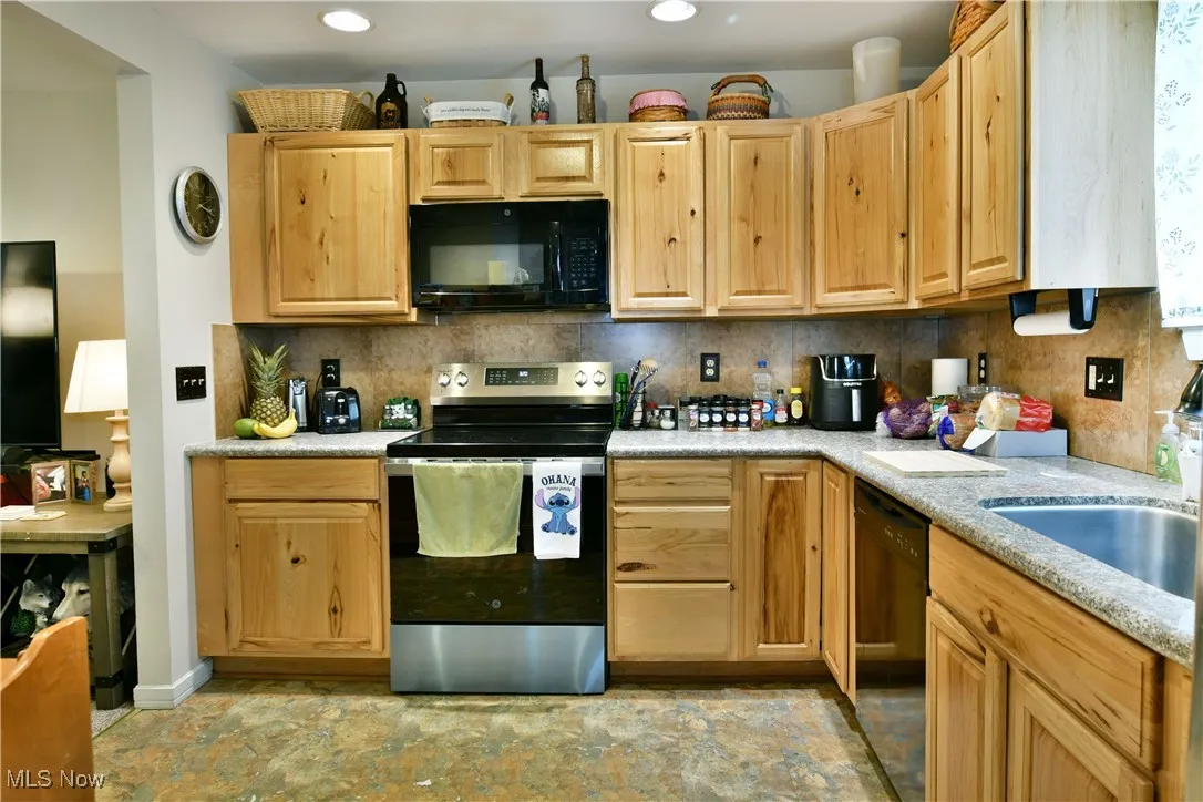 Kitchen featuring black appliances, light brown cabinetry, light countertops, and recessed lighting