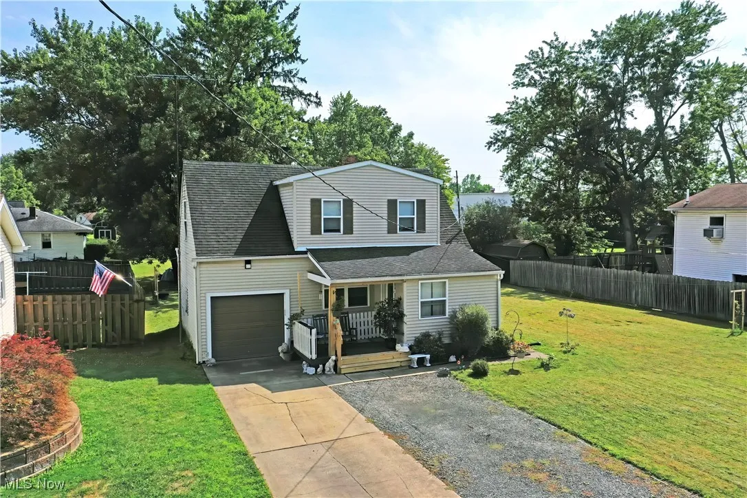 Traditional-style home with gravel driveway, roof with shingles, and a porch