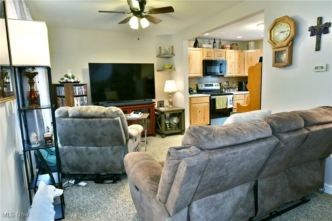 Carpeted living area featuring ceiling fan and recessed lighting