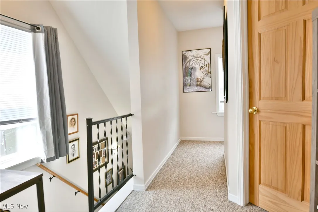 Corridor with light colored carpet and an upstairs landing