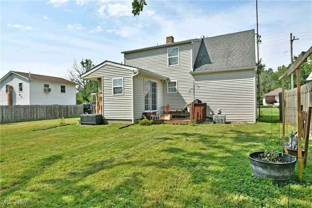 Rear view of property featuring a fenced backyard, a chimney, and a shingled roof