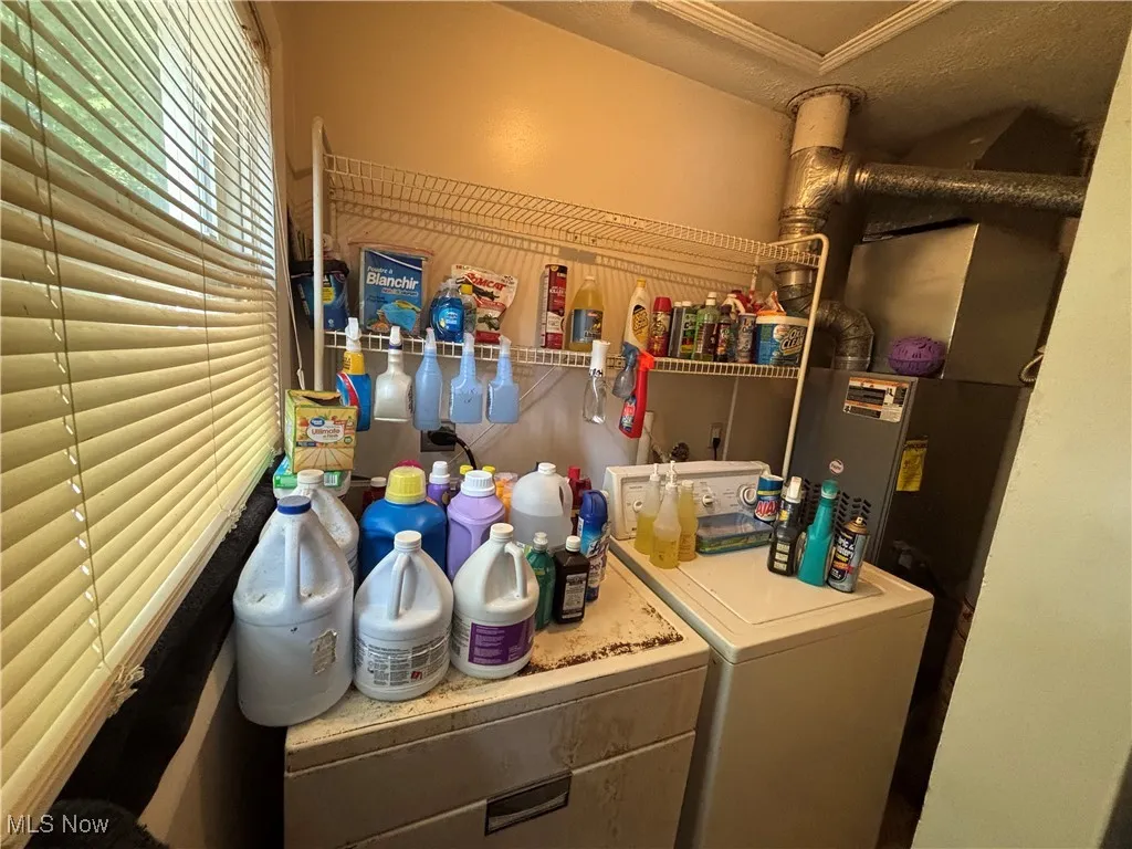 Laundry room featuring washing machine and clothes dryer, heating unit, and ornamental molding