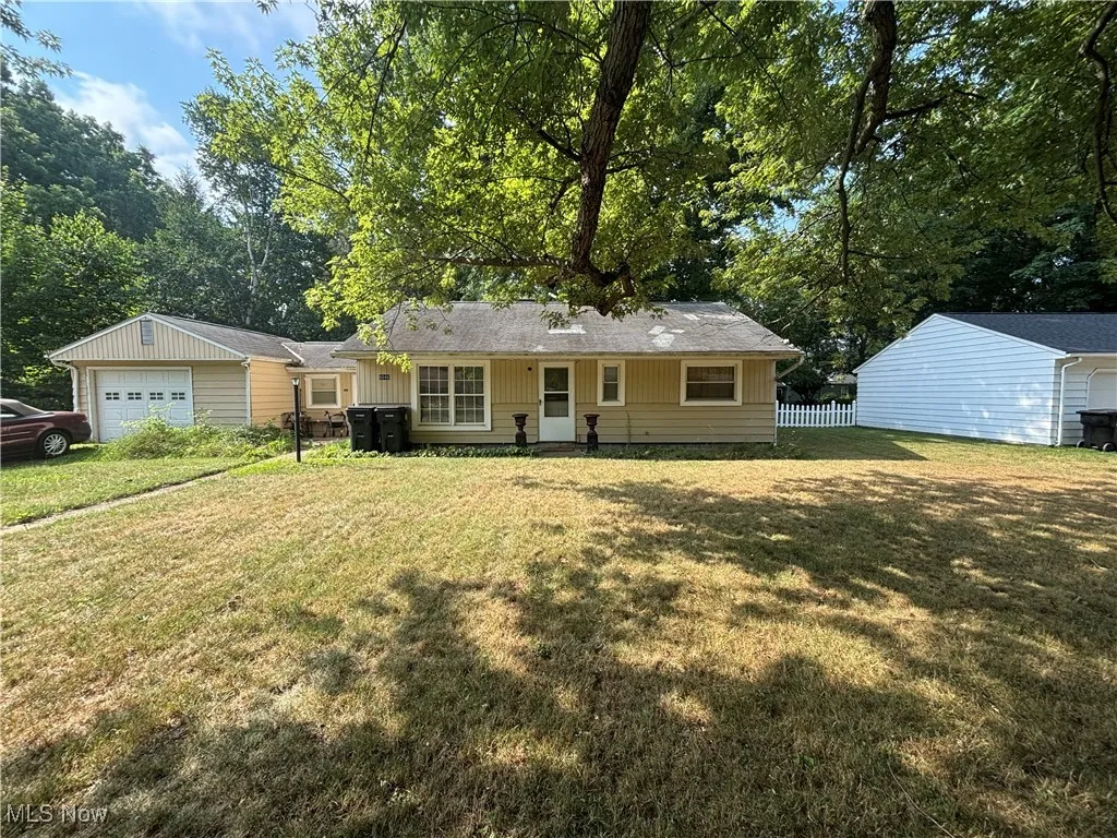 View of front of property with an attached garage, view of wooded area, and board and batten siding