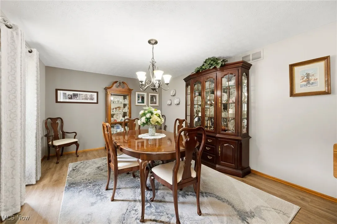 Dining area with a chandelier, light wood-type flooring, and a textured ceiling