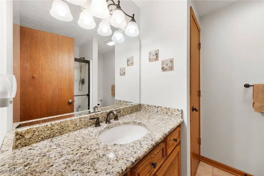 Full bath featuring a shower with door, vanity, and tile patterned flooring