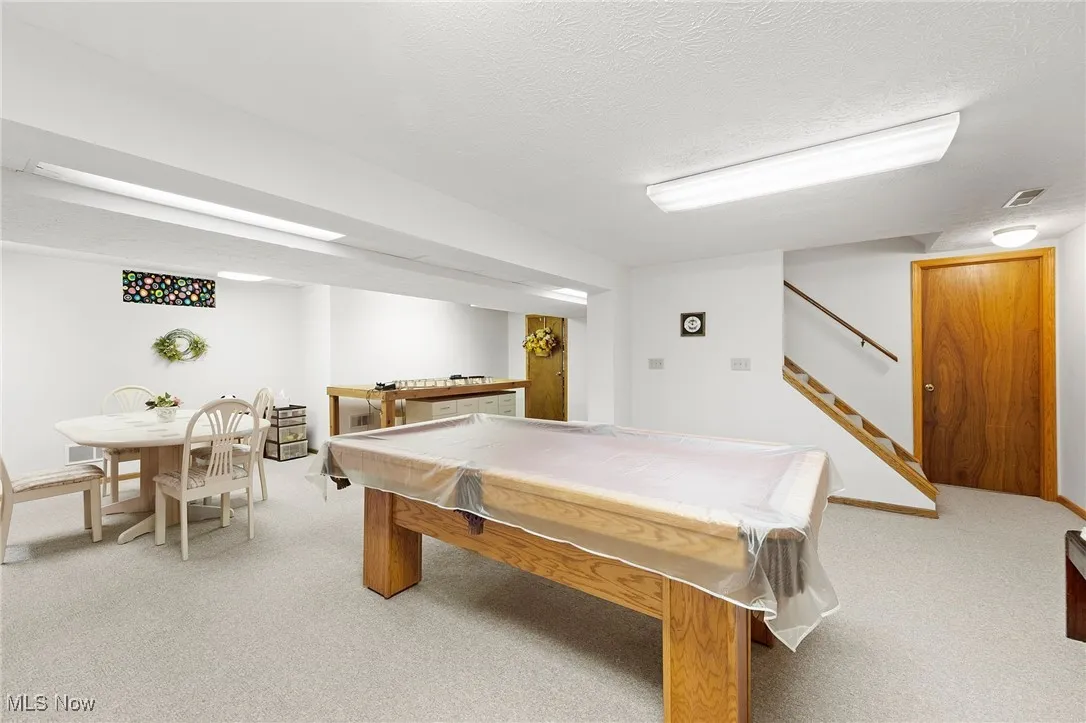 Game room featuring billiards, light colored carpet, and a textured ceiling