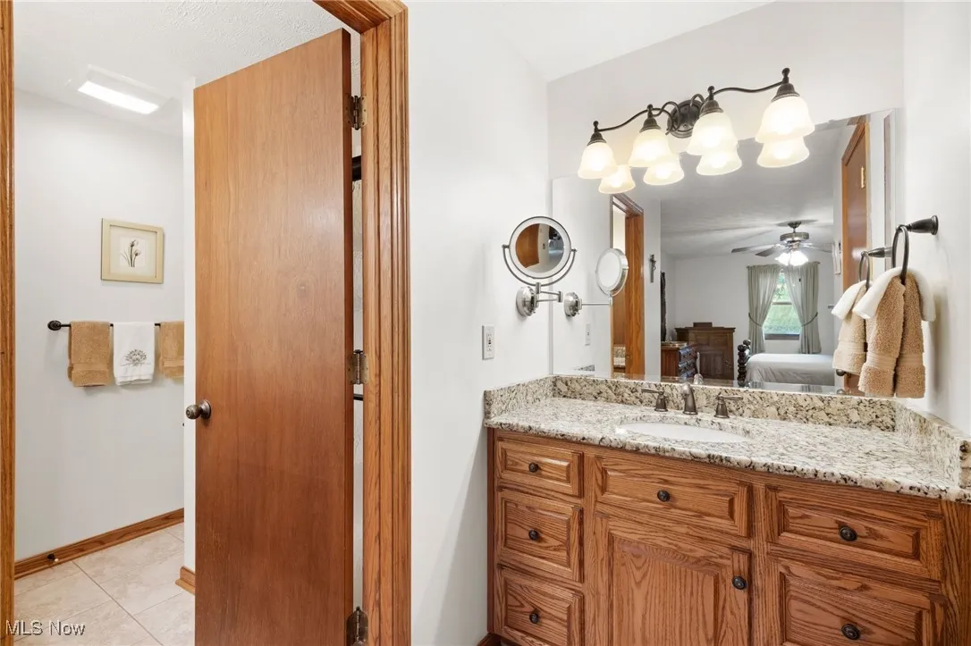 Ensuite bathroom featuring vanity, tile patterned floors, and a ceiling fan