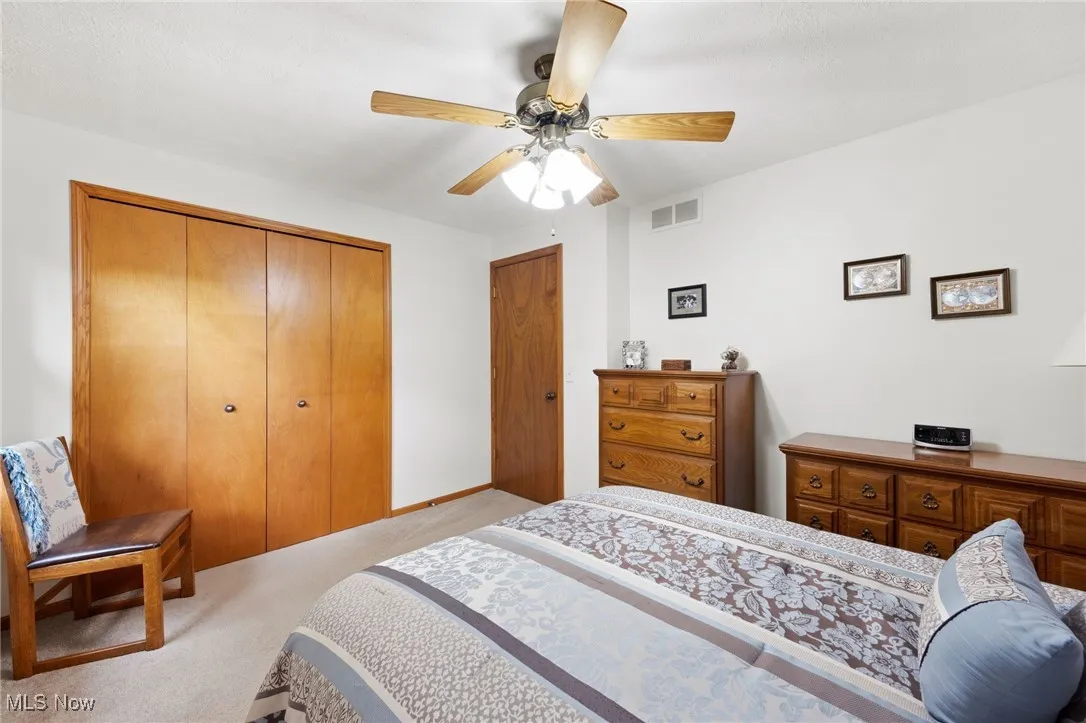 Bedroom with a closet, light carpet, and ceiling fan