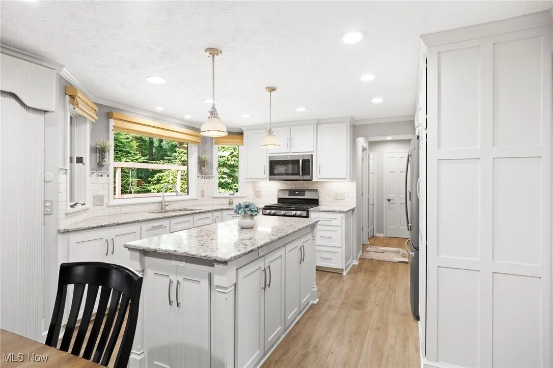 Kitchen with ornamental molding, white cabinetry, a kitchen island, tasteful backsplash, and recessed lighting