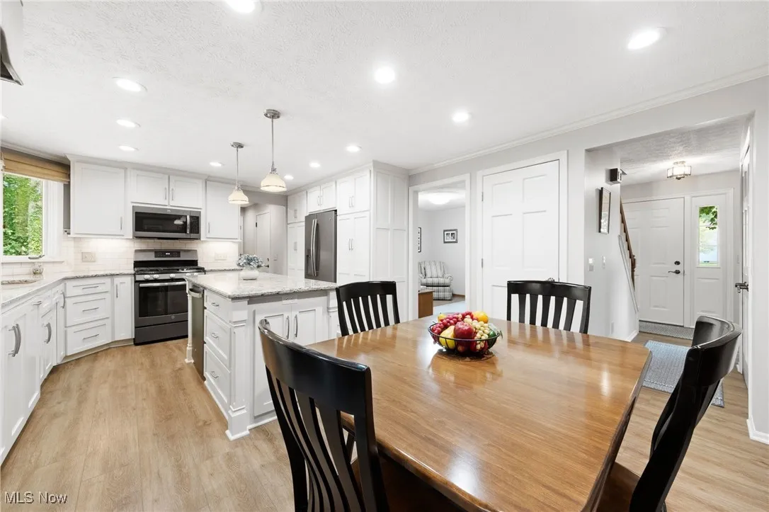 Dining room featuring light wood-type flooring, recessed lighting, ornamental molding, and a textured ceiling