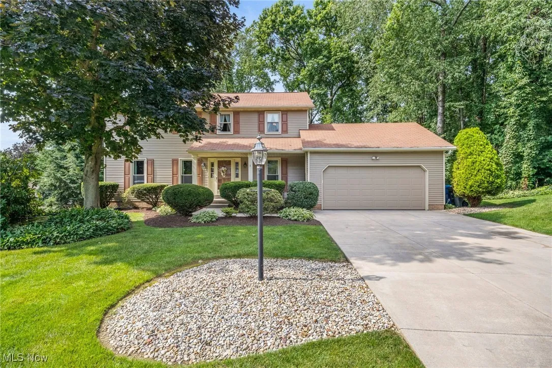 View of front of property with a garage, a front lawn, and driveway