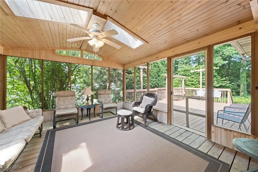 Sunroom featuring ceiling fan, outdoor lounge area, lofted ceiling, and a skylight