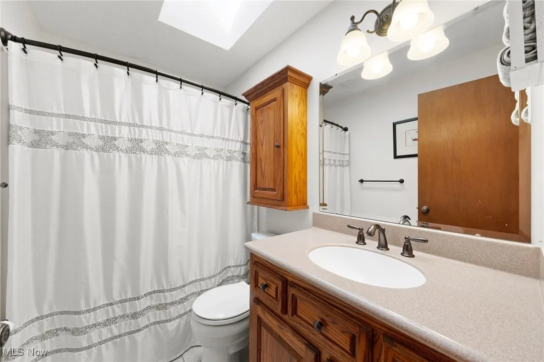 Full bathroom with a skylight, vanity, and curtained shower